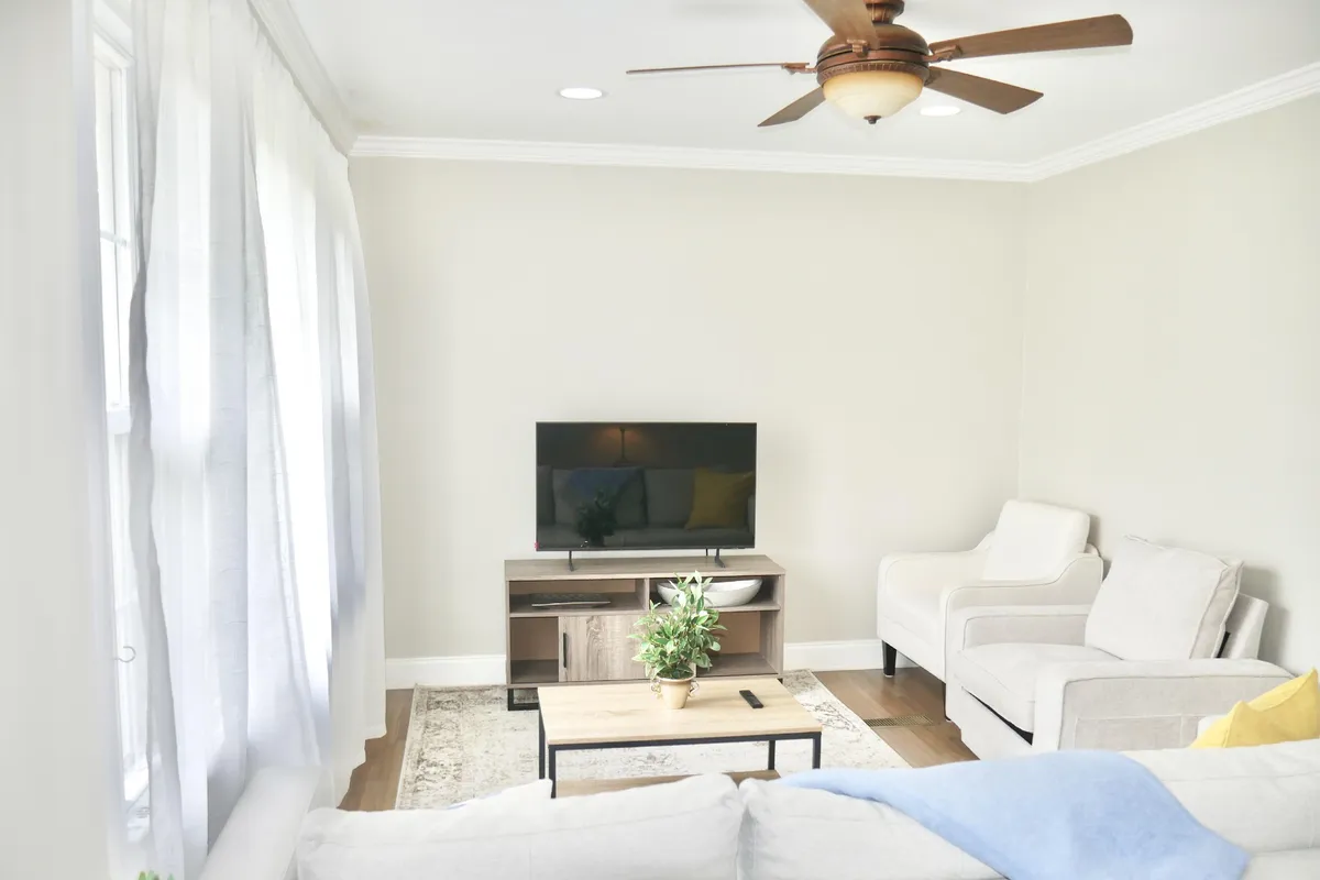 The image showcases a warm and inviting living room with a plush sofa, stylish coffee table, TV for entertainment, and a touch of greenery from a nearby plant. The layout evokes a sense of comfort, making it perfect for relaxing, socializing, or enjoying movie nights with loved ones.