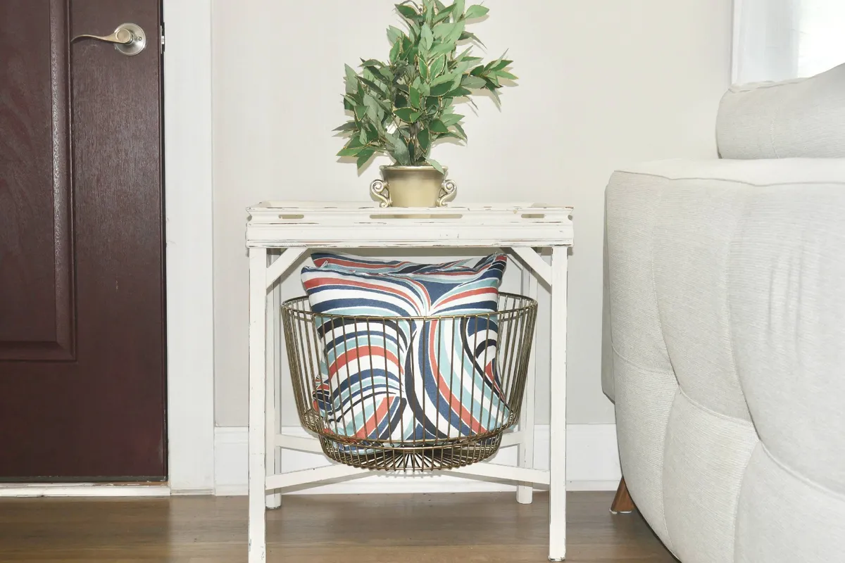 A cheerful corner featuring a decorative plant, colorful pillow, and a vintage table, evoking a cozy spot for coffee, conversation, or planning your next outing.