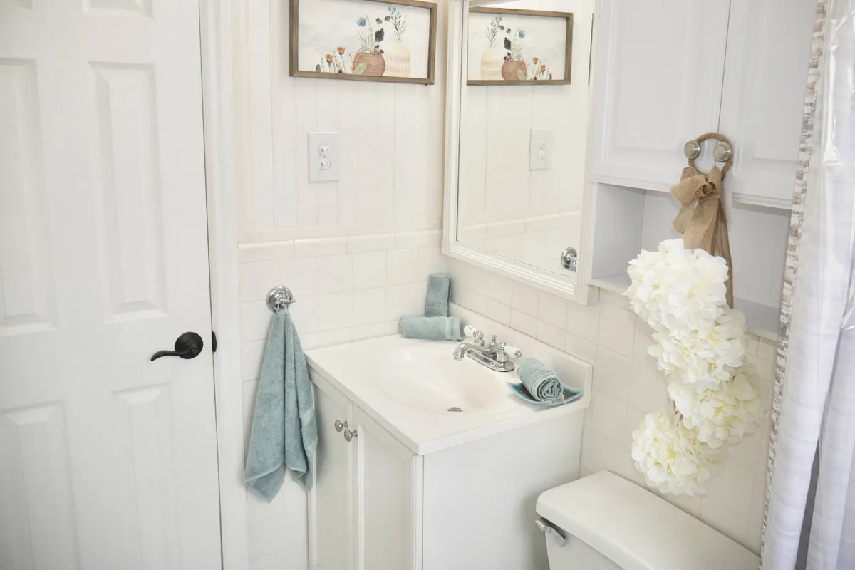 A serene bathroom with a modern sink, fluffy towels, decorative artwork, and a large mirror. The space exudes cleanliness and relaxation, ideal for personal care routines.